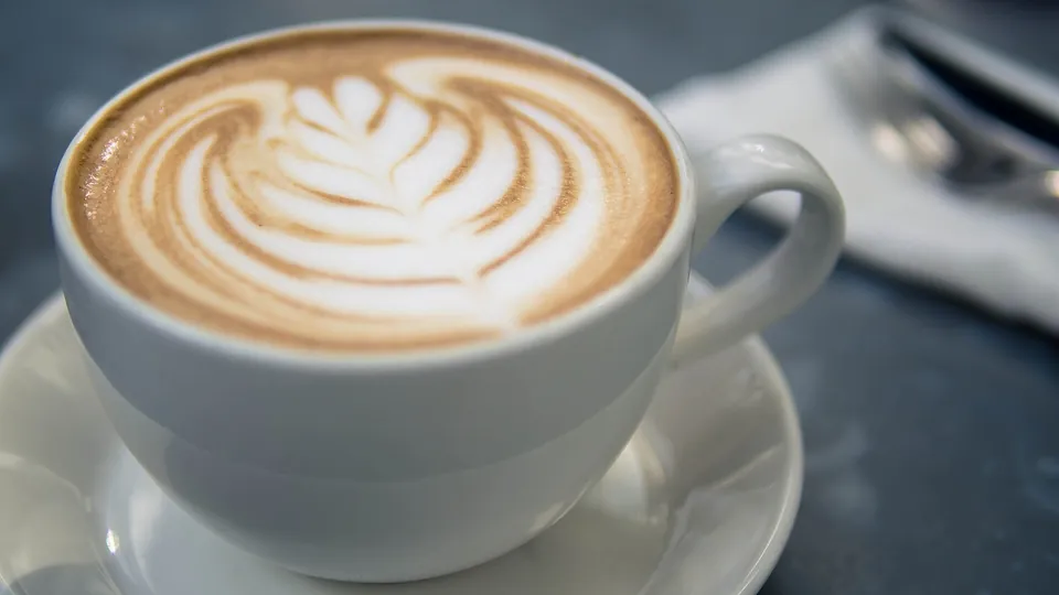 Cappuccino mit Latte-Art-Blatt in einer weißen Tasse